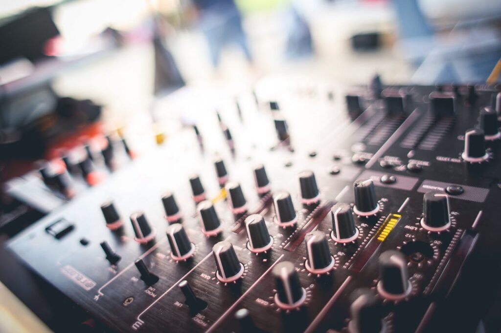 A close-up shot of a DJ mixing panel with various knobs and sliders in a blurred background setting.